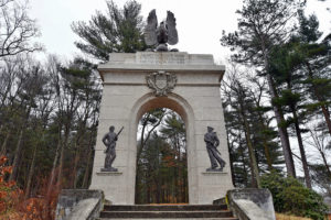 A photograph of a memorial archway with trees in the background.