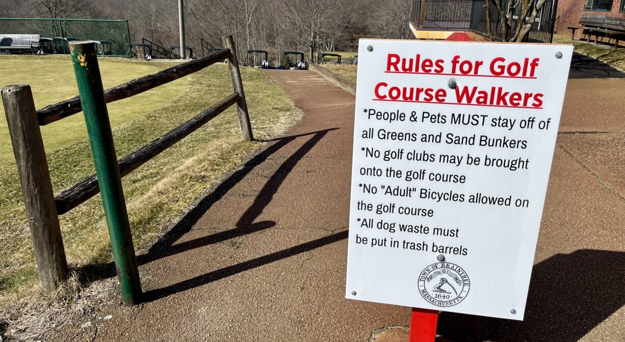 A photograph of a rules sign on a paved pathway.